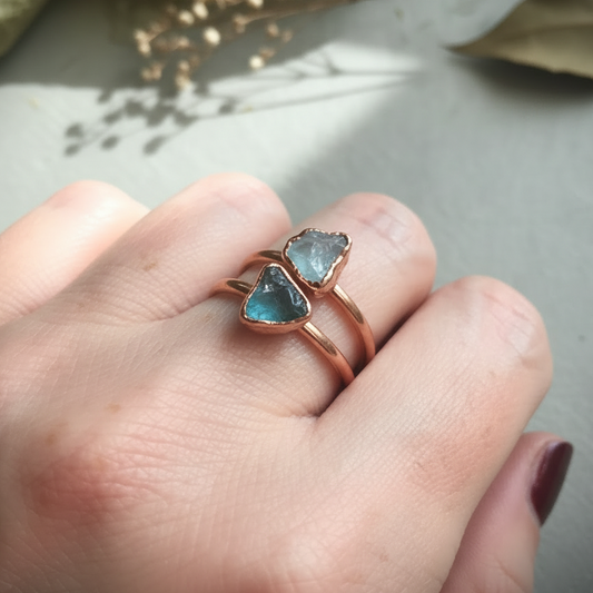 Dainty aquamarine rings hand shot on light grey slate