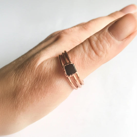 Copper ring with a black gemstone on a wrist against a white background