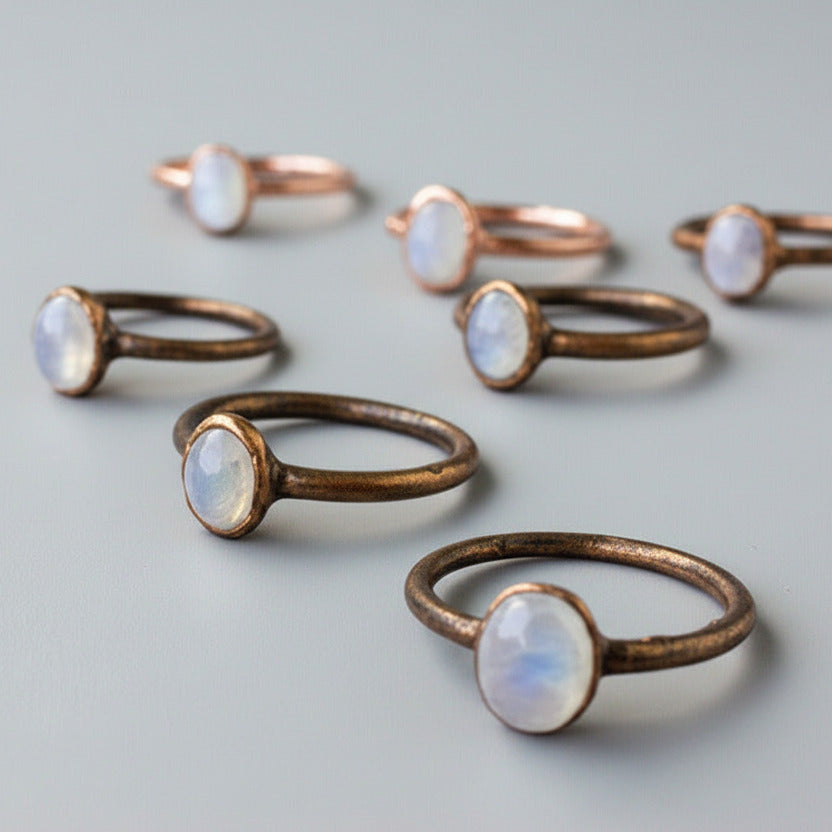 Copper rings with moonstone stones on a light gray background