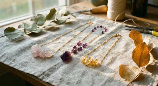 Three layered gemstone necklaces with rose quartz, amethyst, and citrine stones arranged on soft linen fabric in warm natural light.