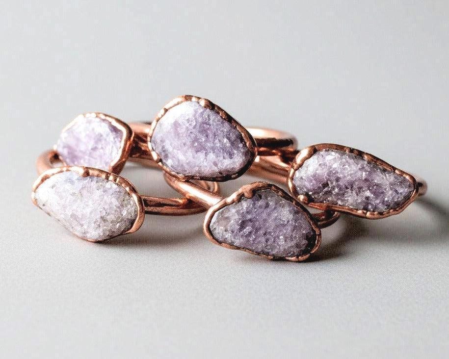 Tumbled lepidolite copper rings showing natural purple and pink stone tones with mica shimmer