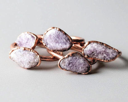 Tumbled lepidolite copper rings showing natural purple and pink stone tones with mica shimmer