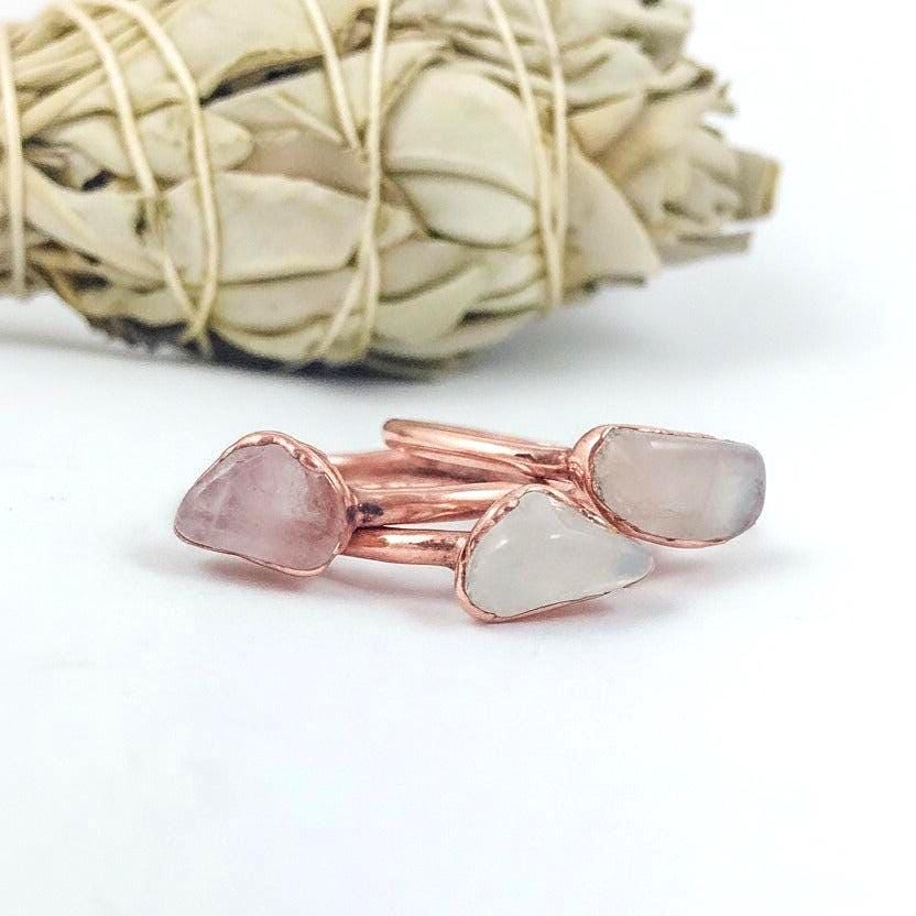 Three dainty rose quartz electroformed copper rings on white background, bright copper finish