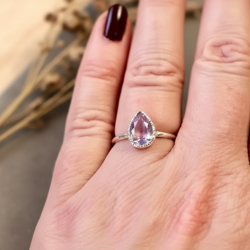 Lavender amethyst silver ring worn on hand with dark burgundy nails, botanical background