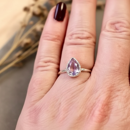 Lavender amethyst silver ring worn on hand with dark burgundy nails, botanical background