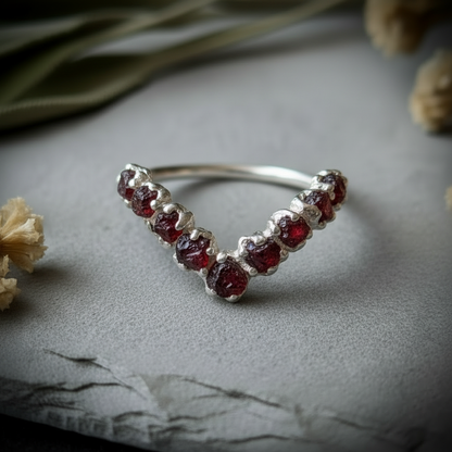 Raw garnet silver-plated chevron ring flat lay overhead on light grey slate