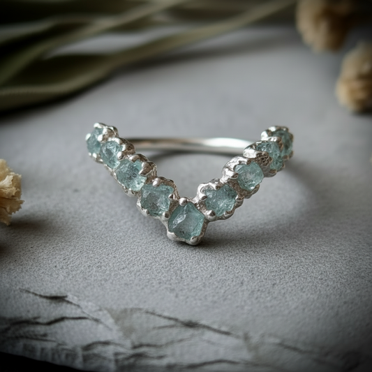 Raw aquamarine sterling silver chevron ring, front view, light grey slate