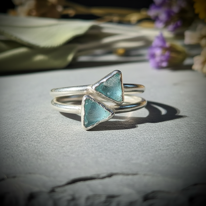 Two dainty raw aquamarine silver stacking rings paired together on slate with dried lavender