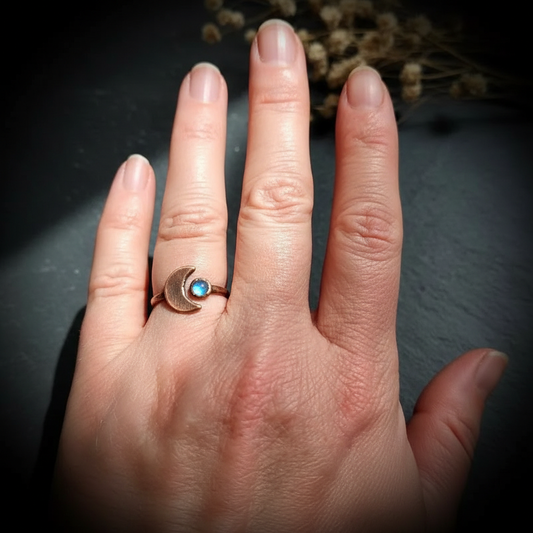 Labradorite crescent moon ring hand shot on dark charcoal slate