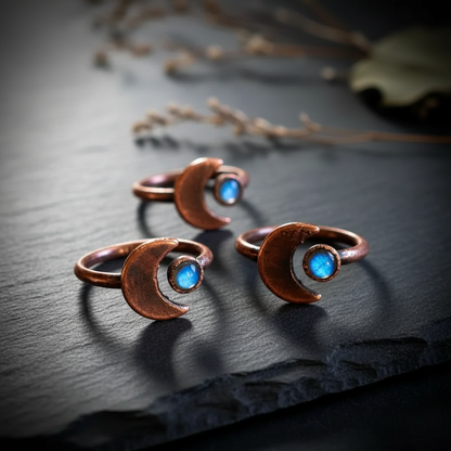 Labradorite crescent moon rings cluster on dark charcoal slate