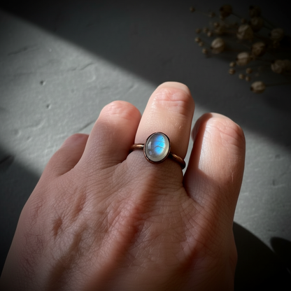 Oval moonstone hand shot on dark charcoal slate