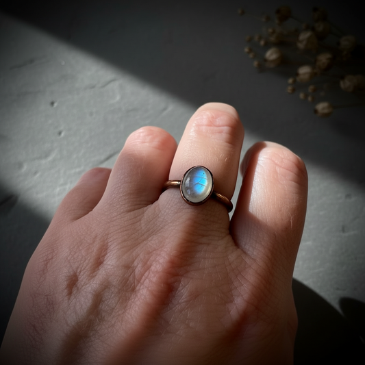 Oval moonstone hand shot on dark charcoal slate